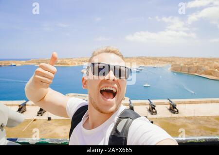 Valletta Malta felice turista uomo in occhiali fa selfie foto sullo sfondo panorama gun Bay Foto Stock