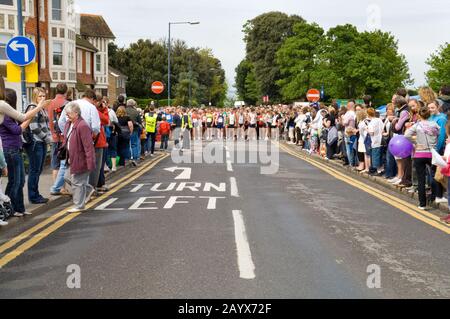 Corridori e spettatori che si raccolgono in strada solo pochi secondi prima dell'inizio di una corsa di beneficenza 10KM Foto Stock