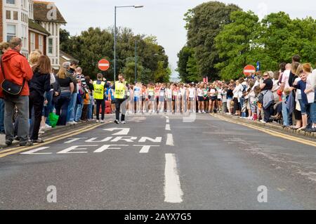 Corridori e spettatori che si raccolgono in strada solo pochi secondi prima dell'inizio di una corsa di beneficenza 10KM Foto Stock