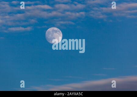 La luna piena in un cielo blu crepuscolo che riflette il sole che tramonta sopra il Parco Nazionale di Yellowstone, Wyoming. Foto Stock