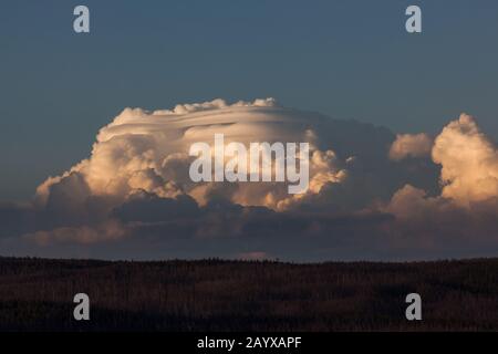Le nuvole di tempesta molto grandi e dinamiche si raccolgono sulle montagne che circondano il Parco Nazionale di Yellowstone e sono illuminate dal sole che tramonta. Foto Stock