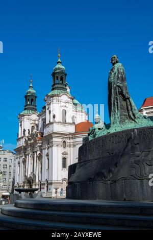 Statua del riformatore religioso Jan Hus con la chiesa barocca di San Nicola nella Piazza della Città Vecchia di Praga, la capitale e la città più grande del ceco Foto Stock