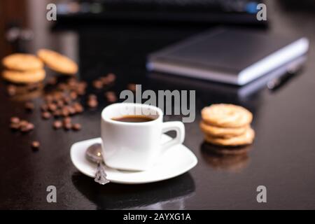 Biscotti al banana con farina d'avena, crema di cioccolato e tazza di caffè in ufficio Foto Stock