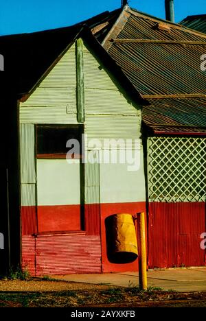 La vecchia casa si è imbarcata in città, con un bidone giallo luminoso nella strada principale dell'Australia Occidentale Foto Stock