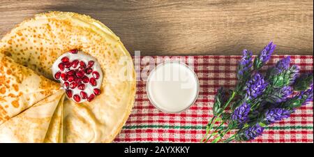 vista dall'alto di pancake tradizionali, marmellata, latte e tovagliolo a motivo quadrato. delizioso dessert tradizionale Foto Stock