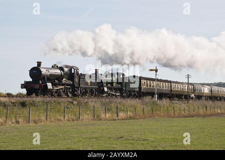 Un treno a doppia testata composto da 6960 Raveningham Hall e 7822 Foxcote Manor tirando una pioggia verso Minehead sulla West Somerset Railway. Foto Stock