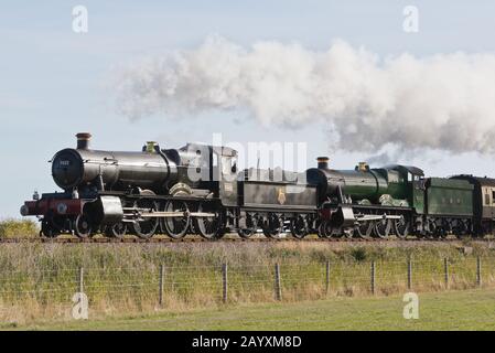 Un treno a doppia testata composto da 6960 Raveningham Hall e 7822 Foxcote Manor tirando una pioggia verso Minehead sulla West Somerset Railway. Foto Stock