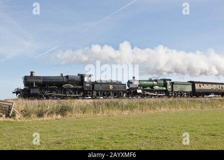 Un treno a doppia testata composto da 6960 Raveningham Hall e 7822 Foxcote Manor tirando una pioggia verso Minehead sulla West Somerset Railway. Foto Stock