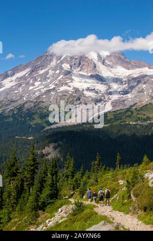 Persone che camminano il Pinnacle Peak Trail nel Mount Rainier National Park con il Monte Rainier sullo sfondo nello stato di Washington, Stati Uniti. Foto Stock