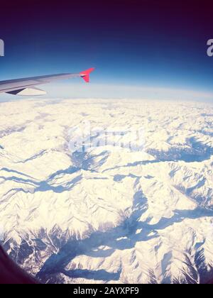 Vista di un'ala dell'aeroplano su montagne invernali innevate Foto Stock