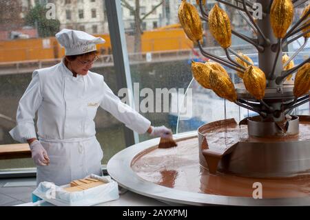 Donna che si tuffa nella fontana di cioccolato nel museo Imhoff-Schokoladenmuseum (museo del cioccolato Imhoff), situato nel quartiere di Colonia di Altstad Foto Stock