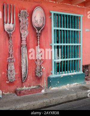 Street art di una forchetta, coltello e cucchiaio decorare l'esterno di un colorato edificio coloniale nel quartiere di San Diego di Cartagena, Colombia Foto Stock