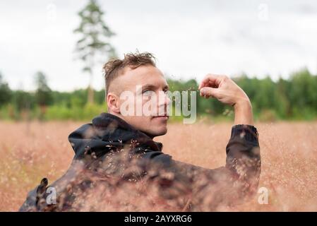 L'uomo siede in un campo spesso, e pensa. Foto Stock