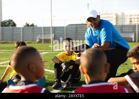 Giocatori di calcio che ascoltano il loro allenatore Foto Stock