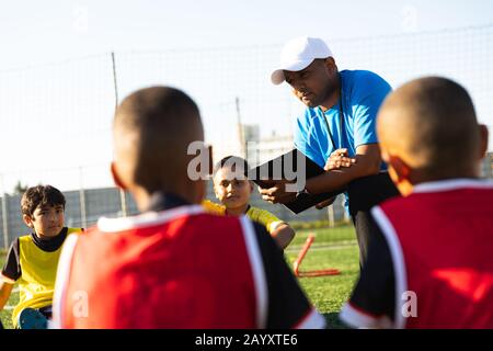 Giocatori di calcio che ascoltano il loro allenatore Foto Stock