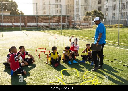 Giocatori di calcio che ascoltano il loro allenatore Foto Stock