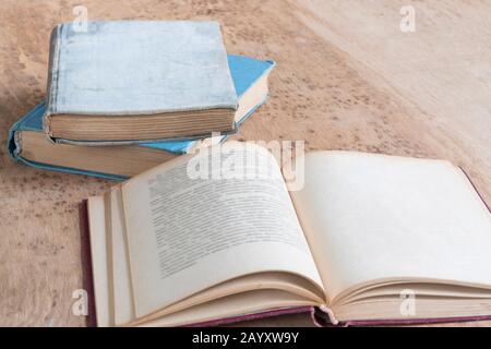 vecchi libri coperti di carta e uno aperto su un tavolo di legno con spazio di copia Foto Stock