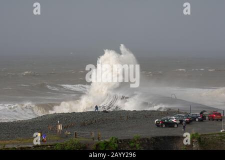 Il clima tempestoso crea grandi onde che si infrangono in Aberystwyth, Galles, mentre gli spettatori sono scondati dalle dimensioni delle onde. Foto Stock