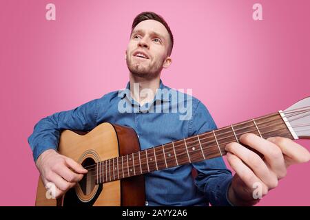 Ritratto di giovane uomo spaventato che accigliava la fronte e nasconde il viso dietro la mano contro sfondo blu Foto Stock