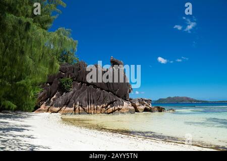 GLACIS rocce scolpite sull'isola di Curieuse, Seychelles. Isola di Praslin sullo sfondo Foto Stock