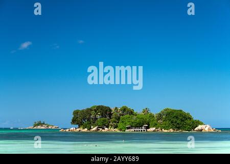 Snorkeling nelle acque tropicali dell'isola di Chauve Souris con St Pierre Islet sullo sfondo. Isola Di Praslin, Seychelles Foto Stock