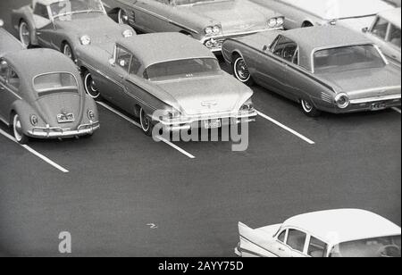 1964, storico, vista aerea di automobili americane dell'epoca parcheggiata in un parcheggio, California, USA, mostrando anche un Maggiolino Volkswagen. Foto Stock