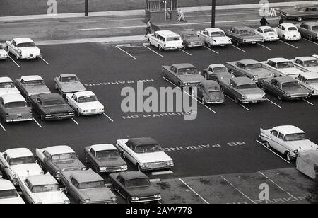 1964, storico, vista aerea delle automobili americane dell'epoca parcheggiata in un parcheggio, California, USA, mostrando anche un certo numero di Volkswagen Beetles. Foto Stock