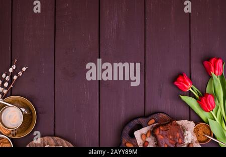 Espresso fresco aromatico e brownie, su un tavolo di legno. Colazione di primavera, fiori, tulipani, dolci e caffè. Vista dall'alto. Spazio libero per il testo Foto Stock