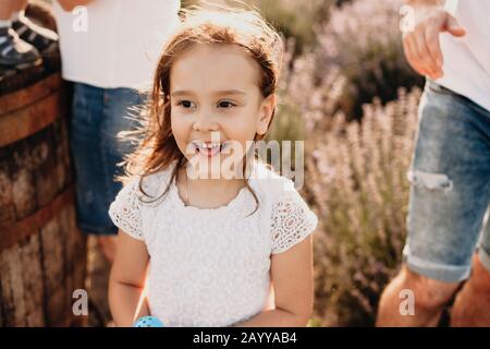 Una ragazza affascinante che posa in un campo di lavanda è sorridente felicemente ed avendo gioia circondata da un sacco di emozioni Foto Stock