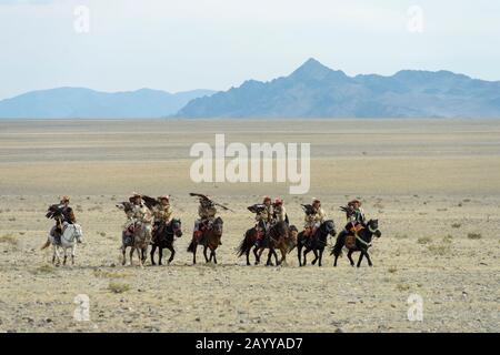 Un gruppo di cacciatori di aquila kazaka e le loro aquile d'oro che arrivano al Golden Eagle Festival Grounds vicino alla città di Ulgii (Ölgii) nel Bayan-Ulgi Foto Stock