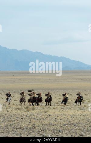 Un gruppo di cacciatori di aquila kazaka e le loro aquile d'oro che arrivano al Golden Eagle Festival Grounds vicino alla città di Ulgii (Ölgii) nel Bayan-Ulgi Foto Stock