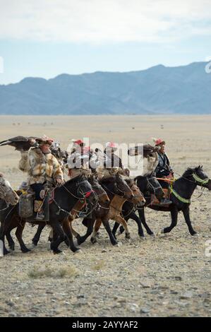 Un gruppo di cacciatori di aquila kazaka e le loro aquile d'oro che arrivano al Golden Eagle Festival Grounds vicino alla città di Ulgii (Ölgii) nel Bayan-Ulgi Foto Stock