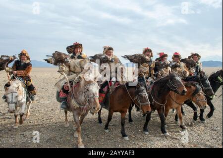 Un gruppo di cacciatori di aquila kazaka e le loro aquile d'oro che arrivano al Golden Eagle Festival Grounds vicino alla città di Ulgii (Ölgii) nel Bayan-Ulgi Foto Stock