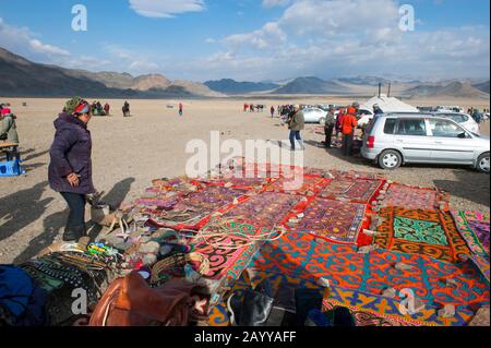 Un venditore che vende tappeti e altri prodotti presso il Golden Eagle Festival Grounds vicino alla città di Ulgii (Ölgii) nella provincia di Bayan-Ulgii nel Mongo occidentale Foto Stock