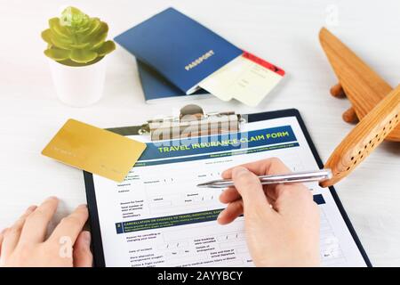 Modulo di richiesta assicurazione di viaggio con carta d'imbarco e passaporto su tavolo di legno bianco. Concetto di politica di viaggio. Foto Stock