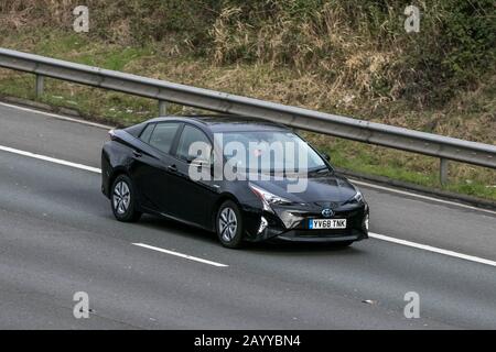 Toyota Prius Business Edtn Vvt-i Cvt vettura nera ibrida movimento del veicolo elettrico guidando sull'autostrada M6 vicino Preston in Lancashire Foto Stock