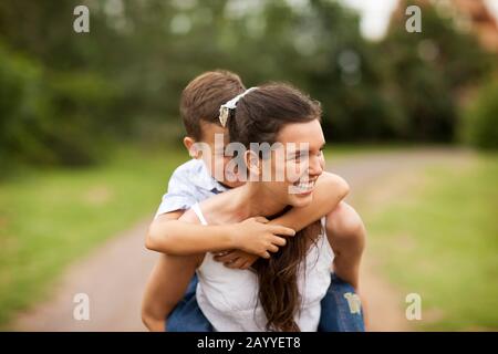 Ragazza adolescente piggybacking suo fratello piccolo. Foto Stock