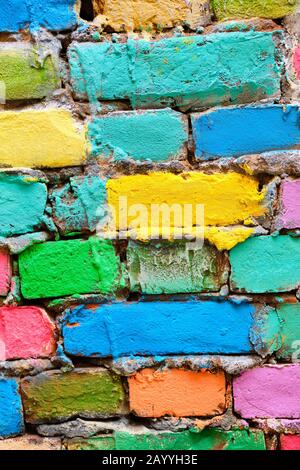 muro di mattoni sbriciolati in diversi colori dipinti. Verticale. Primo piano. Foto Stock