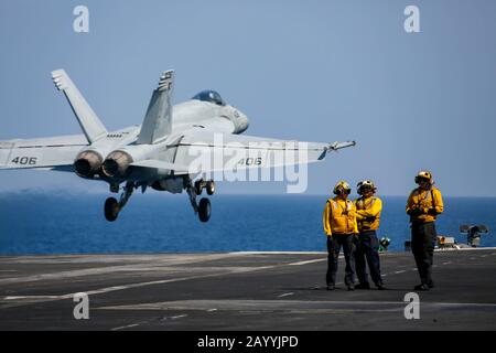 Giubbotti gialli della Marina degli Stati Uniti guardano il lancio di un aereo da combattimento F/A-18E Super Hornet attaccato al pugno della flotta dello Strike Fighter Squadron 25 decollare dal ponte di volo portaerei della classe Nimitz USS Abraham Lincoln 26 ottobre 2019 operante nel Mar Arabico. Foto Stock