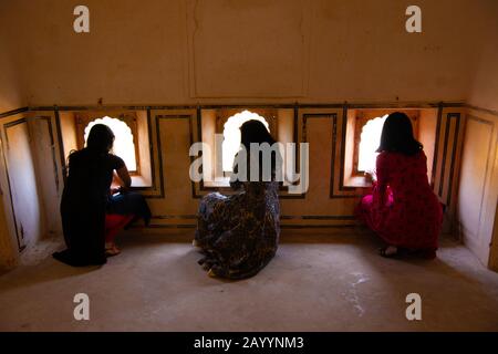 I visitatori e i turisti guardano fuori le finestre mentre esplorano l'antico Forte Amber in Amer, Rajasthan, India. Foto Stock