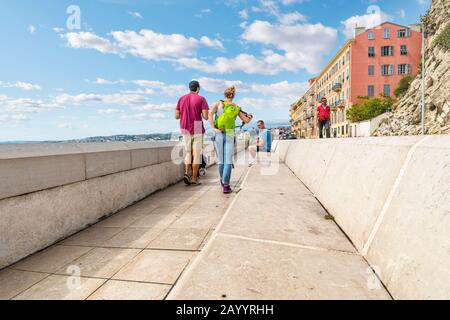 Una giovane coppia cammina il cane lungo il sentiero pedonale nella baia degli Angeli, sulla Riviera francese a Nizza, Francia. Foto Stock