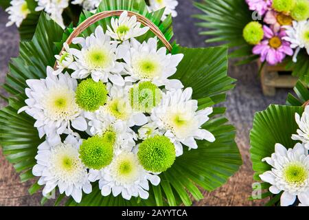 Vista ravvicinata di un bouquet di fiori bianchi e verdi luminosi splendidamente disposti in un cesto, circondati da fiori più colorati e rosa, Asia Foto Stock