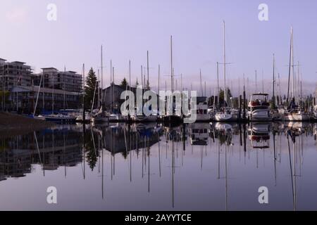 Barche Ormeggiate A Marina Con Idilliaca Acqua In Piedi Contro Una Bella Nuvoloso Alba Foto Stock