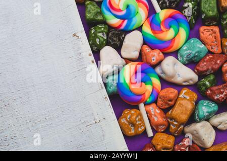 Lecca-lecca e ciottoli di caramella. Dolci in forma di pietre colorate. Sfondo colorato con caramelle colorate. Decorazione festosa. Spazio copia Foto Stock