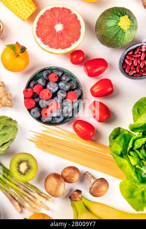 Cibo vegano, dieta sana piatto. Frutta, verdura, legumi, funghi, pasta, sparata dall'alto su sfondo bianco Foto Stock