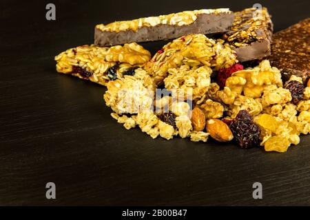 Barrette di granola con noci tostate, fuoco selettivo. Bar con farinata d'avena e noci su sfondo nero. Nutrizione per gli atleti. Dolcezza vegetariana. Foto Stock