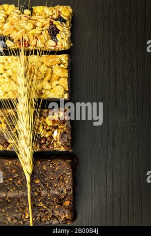 Barrette di granola con noci tostate, fuoco selettivo. Bar con farinata d'avena e noci su sfondo nero. Nutrizione per gli atleti. Dolcezza vegetariana. Foto Stock