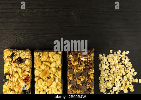 Barrette di granola con noci tostate, fuoco selettivo. Bar con farinata d'avena e noci su sfondo nero. Nutrizione per gli atleti. Dolcezza vegetariana. Foto Stock