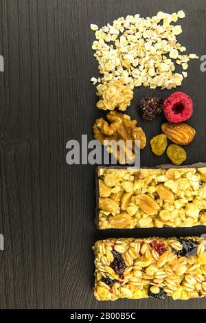 Barrette di granola con noci tostate, fuoco selettivo. Bar con farinata d'avena e noci su sfondo nero. Nutrizione per gli atleti. Dolcezza vegetariana. Foto Stock