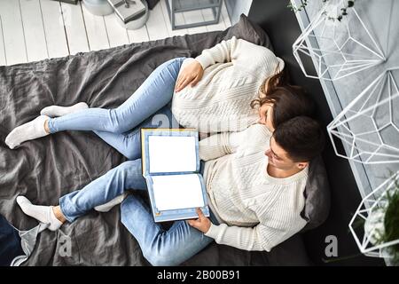 coppia incinta amorevole, sdraiati sul letto e guardarsi l'un l'altro. In attesa del bambino, una nuova vita, felicità e problemi di una giovane famiglia Foto Stock